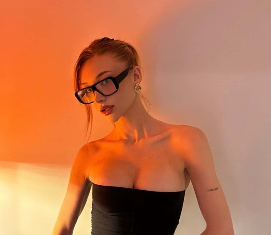 Elegant woman wearing glasses and black strapless top with warm lighting.