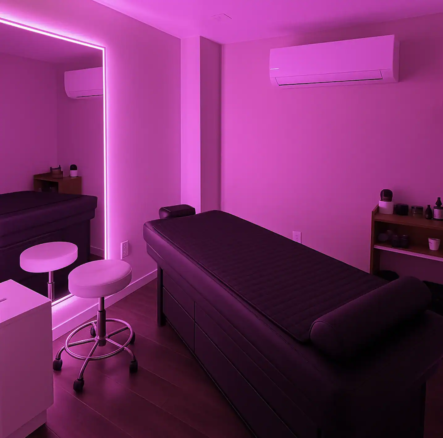 Relaxing massage room illuminated with pink LED lights, featuring comfortable massage table and tranquil decor.