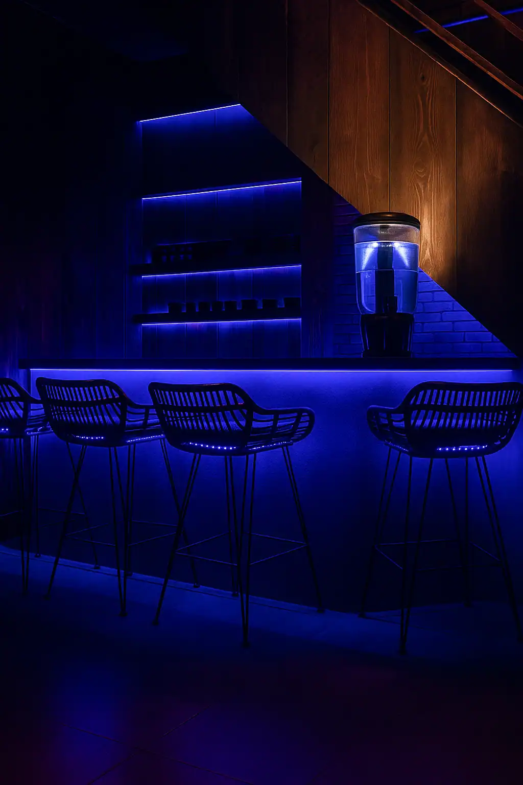 Modern bar with blue LED lighting, sleek furniture, and contemporary design.
